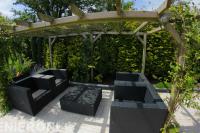 Zithoek met loungeset onder houten pergola