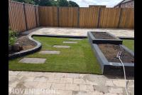 Tuinaanleg met bestrating, graszoden, plantenbakken en schutting