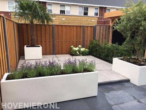 Moderne tuin met witte plantenbakken en grote tegels