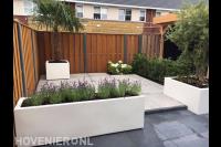 Moderne tuin met witte plantenbakken en grote tegels