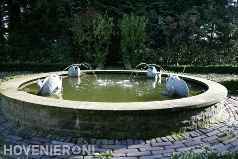 Kleine ronde vijver met fonteinen in vorm van vissen