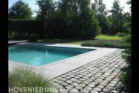 Bestrating van kasseien en grote tegels bij zwembad