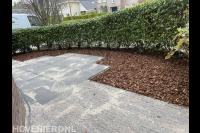 Bestrating gereinigd en boomschors in de borders aangebracht