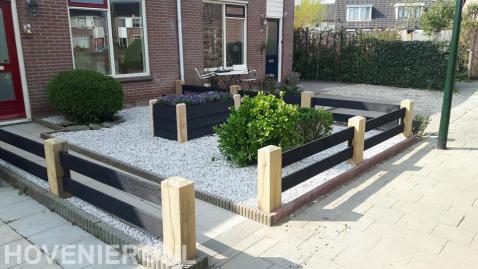 Onderhoudsarme voortuin met houten hekwerk en plantenbak