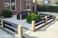 Onderhoudsarme voortuin met houten hekwerk en plantenbak
