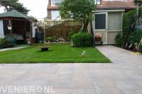 Achtertuin met tuinhuisje, gazon en siertegels