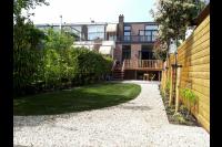 Achtertuin met gazon, grind en verhoogd terras van hout