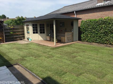 Tuinaanleg met graszoden en houten tuinhuis met overkapping en vlonder