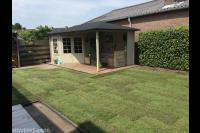 Tuinaanleg met graszoden en houten tuinhuis met overkapping en vlonder