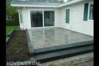 Verhoogd terras van siertegels met trappetje bij bungalow