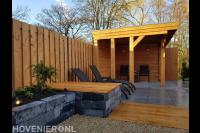 Plantenbak met zitje in tuin met houten overkapping