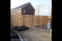 Tuinaanleg met houten schutting, sierbestrating en leibomen