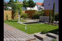 Tuin met houten schutting, gazon en vijver met watermuur en vlonder