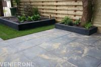 Plantenbakken van stapelblokken en straatwerk van antraciet tuintegels