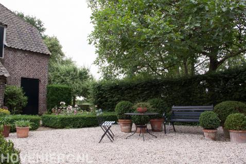 Klassieke tuin met grind en buxusbollen in bloempotten