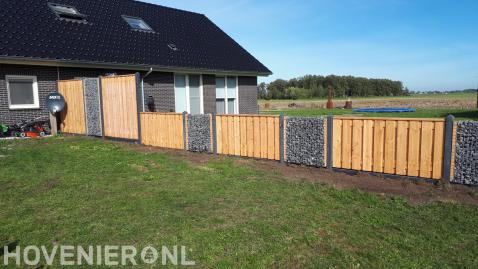 Schutting met houten schermen afgewisseld met schanskorven