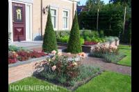 Voortuin met kleurrijke beplanting en vormsnoei van coniferen