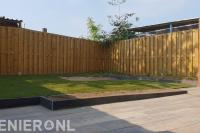 Tuinaanleg met bestrating, gazon en houten schutting