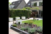 Achtertuin met terras, gazon, bloembakken en border