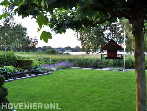 Tuin met vijver en gazon met uitzicht op water