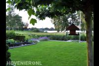 Tuin met vijver en gazon met uitzicht op water
