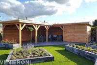 Tuinaanleg met gazon, plantenbakken en grote houten overkapping