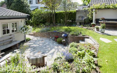 Trappetje vanaf gazon naar lagergelegen terras bij tuinhuis