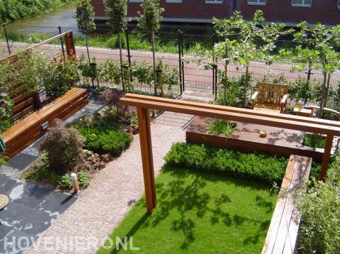 Moderne gezinstuin met pergola, vlonder en zitbankjes