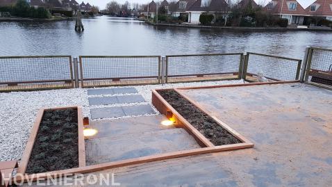 Tuin aan het water met verhoogd terras, grind en hekwerk