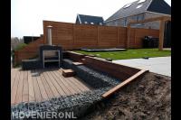 Vlonderterras aan het water met tuinhaard in schanskorf