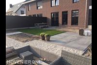 Tuinaanleg met bestrating van grote siertegels, grind en gazon