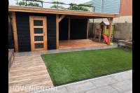 Tuin met bestrating, kunstgras en houten schuurtje met overkapping