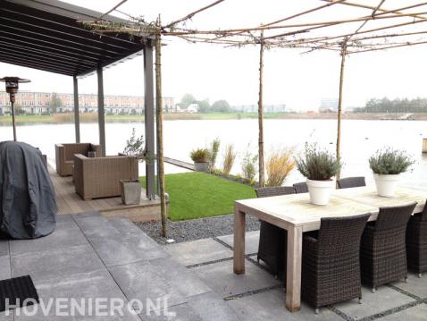 Tuin aan het water met overkapping, vlonder, terras en gazon