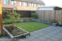 Tuinaanleg met bestrating, plantenbakken en gazon