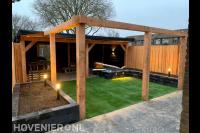 Tuinaanleg met kunstgras, plantenbakken, overkapping en pergola