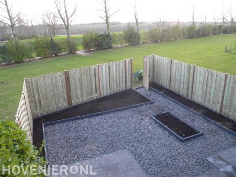 Tuin met houten schutting en verharding van split en tuintegels