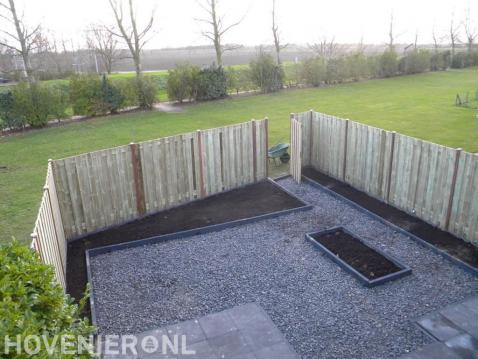 Tuin met houten schutting en verharding van split en tuintegels