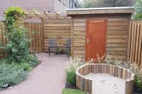 Achtertuin met houten schutting, berging en zandbak