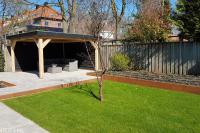 Tuin met robuuste houten overkapping, gazon en borders van cortenstaal