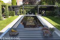 Moderne vijver met waterornamenten en terras met zonnedoek.