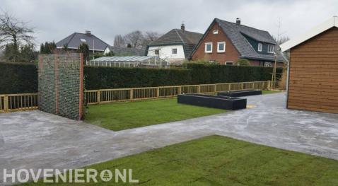 Tuinaanleg met bestrating, graszoden, plantenbakken en houten tuinhek