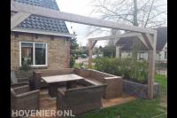 Terras aanleggen met houten pergola en plantenbak