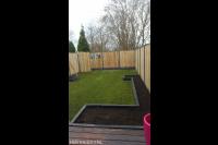 Tuinaanleg met graszoden, borders en hout beton schutting met poort