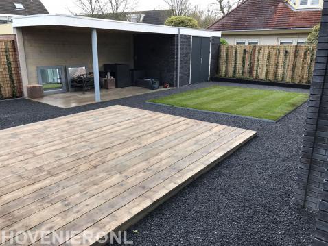 Tuin met vlonder, kunstgras en schuur met overkapping