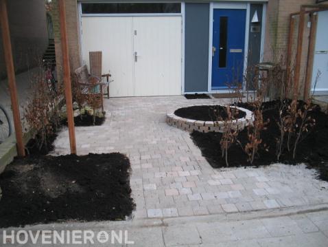 Kleine voortuin met pergola en bestrating van koppelstenen