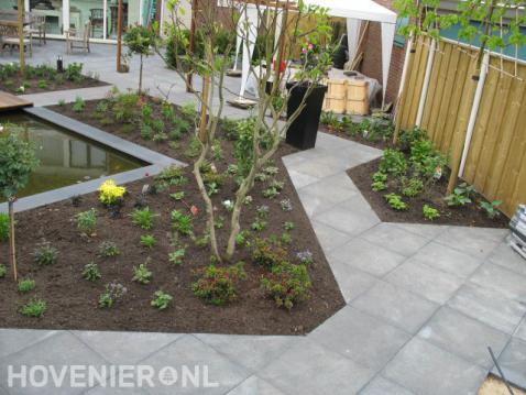Strakke tuin met vijver, borders en grote tegels