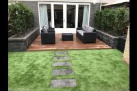 Tuinaanleg met kunstgras, houten vlonder en plantenbakken