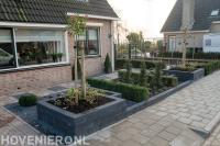 Voortuin met klinkers, buxus en plantenbakken van stapelblokken
