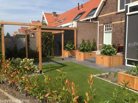 Achtertuin met kunstgras, pergola en houten plantenbakken