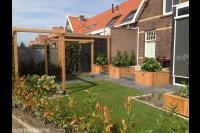 Achtertuin met kunstgras, pergola en houten plantenbakken